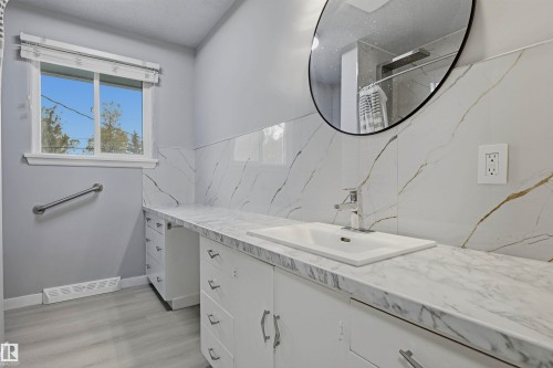 Vanity with an integrated sink, polished chrome faucet, and white cabinetry - 13024 Sherbrooke Avenue Nw, Edmonton, AB 