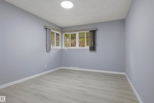 Recessed ceiling light fixture, corner windows, light wood-finish flooring, white baseboards, and light blue wall finish - 13024 Sherbrooke Avenue Nw, Edmonton, AB 