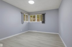 Recessed ceiling light fixture, corner windows, light wood-finish flooring, white baseboards, and light blue wall finish - 