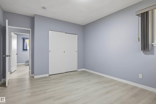 Wood-finish flooring, sliding closet doors, and a window with vertical blinds - 13024 Sherbrooke Avenue Nw, Edmonton, AB 