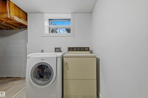 Laundry area featuring a window, painted walls, and wood-finish flooring - 13024 Sherbrooke Avenue Nw, Edmonton, AB 