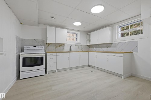 White cabinetry with wood-finish countertops, subway tile backsplash, and light wood-finish flooring - 13024 Sherbrooke Avenue Nw, Edmonton, AB 