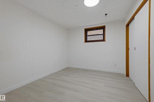 Light wood-finish flooring, white walls, and a single window with dark wood trim - 13024 Sherbrooke Avenue Nw, Edmonton, AB 