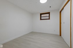 Light wood-finish flooring, white walls, and a single window with dark wood trim - 