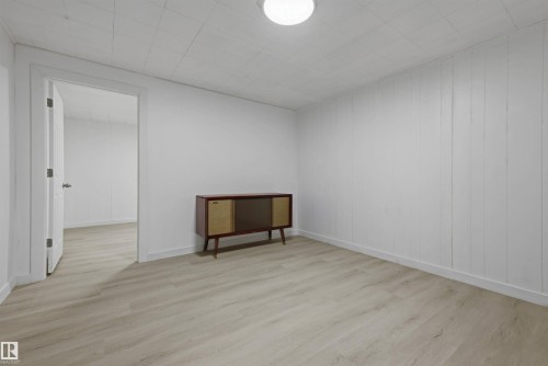 Light wood-finish flooring with white paneled walls and ceiling - 13024 Sherbrooke Avenue Nw, Edmonton, AB 
