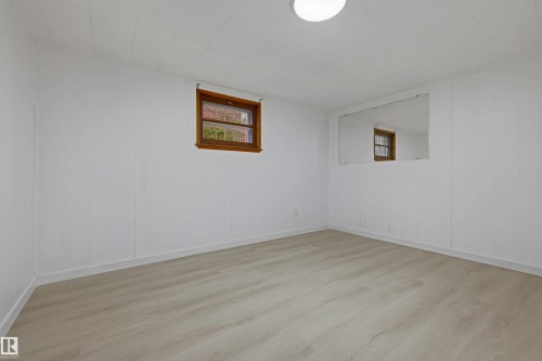 Room featuring light wood-finish flooring, white paneled walls, and a recessed window with wood trim - 13024 Sherbrooke Avenue Nw, Edmonton, AB 