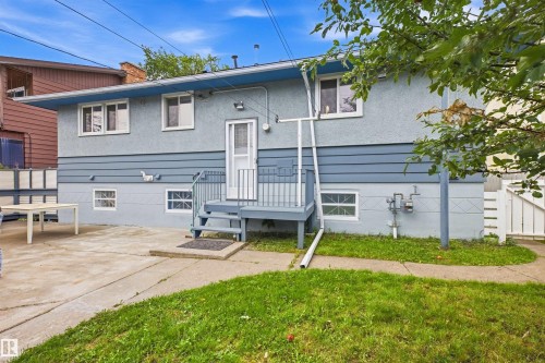 Stucco exterior with horizontal siding accents, rear deck with railings, concrete patio, and a fenced perimeter - 13024 Sherbrooke Avenue Nw, Edmonton, AB 
