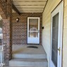 Brick exterior with a concrete porch and steps, featuring a full-light storm door and a wall-mounted light fixture - 11022 158 Avenue Nw, Edmonton, AB 