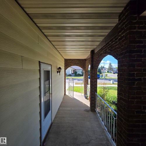 Covered porch featuring brick archways, concrete flooring, and decorative metal railings - 11022 158 Avenue Nw, Edmonton, AB 