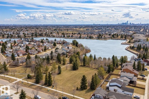 Expansive neighborhood featuring a large central lake, mature trees, and a distant cityscape - 11022 158 Avenue Nw, Edmonton, AB 