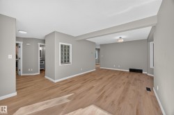 Open-concept living space featuring wood-finish flooring, recessed lighting, and a glass block window - 