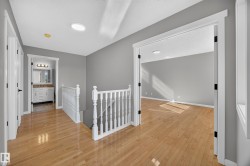 Hardwood flooring throughout, white trim and doors, contemporary gray wall tones, recessed lighting, and a white vanity with a rectangular sink - 