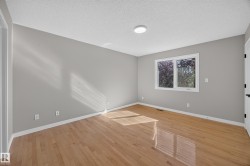 Wood-finish flooring, white trim, and a window with white casing - 