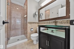 Glass-enclosed shower with a built-in bench, a vessel sink vanity, a framed mirror, and mosaic tile accents - 