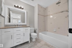 White vanity with a speckled countertop, undermount sink, and brushed nickel faucet - 