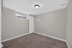 Bedroom 6.  Neutral gray walls, dark brown carpet, white trim, frosted glass window, and a white interior door - 