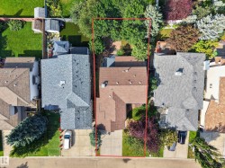 Residential property with a paved driveway, front lawn, and mature trees - 