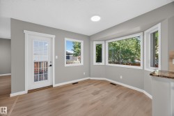 Recessed lighting, wood-finish flooring, bay window, light gray wall finishes, and a glass-paneled door - 