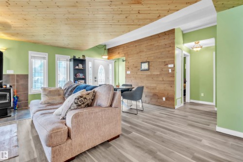 Open-concept living space featuring wood-finish flooring, a natural wood plank ceiling, and an accent wood plank wall - 5103 50 Street, Cold Lake, AB - Indoor Photo Showing Living Room