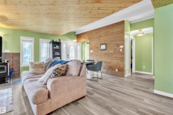 Open-concept living space featuring wood-finish flooring, a natural wood plank ceiling, and an accent wood plank wall - 