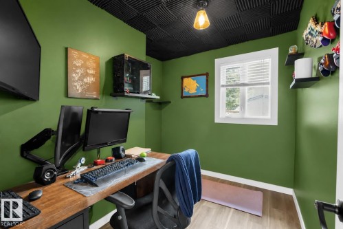 Dedicated workspace featuring a wood-finish desk with storage, light wood-finish flooring, and a single window with blinds - 5103 50 Street, Cold Lake, AB - Indoor Photo Showing Office