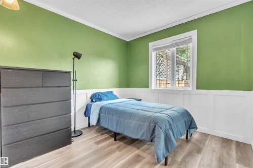 Bedroom featuring green painted walls, white wainscoting, wood-finish flooring, and a window with white trim - 5103 50 Street, Cold Lake, AB - Indoor Photo Showing Bedroom