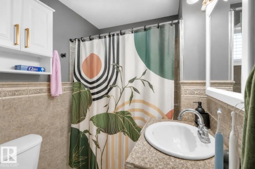 Bathroom featuring a single basin sink with chrome faucet, granite-look countertop, and a built-in white vanity cabinet with gold-finish pulls - 5103 50 Street, Cold Lake, AB - Indoor Photo Showing Bathroom