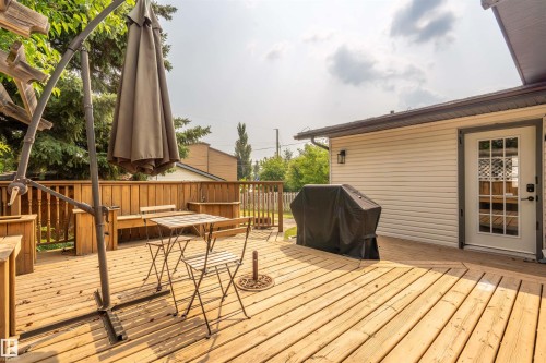 Spacious wood deck featuring built-in wooden benches, natural wood railing, and a white siding exterior with an exterior light fixture - 5103 50 Street, Cold Lake, AB - Outdoor With Deck Patio Veranda With Exterior