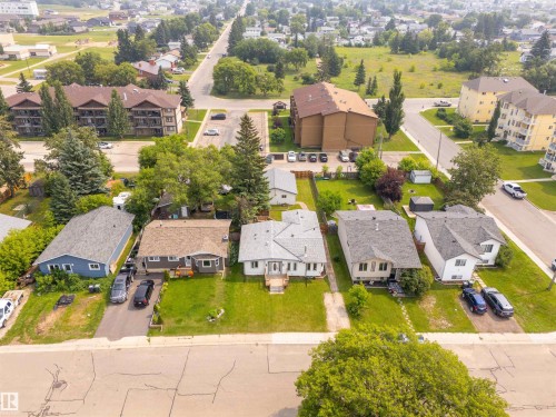 Aerial perspective showcasing a residential street with single-story homes, a multi-story apartment building, and surrounding green spaces - 5103 50 Street, Cold Lake, AB - Outdoor With View