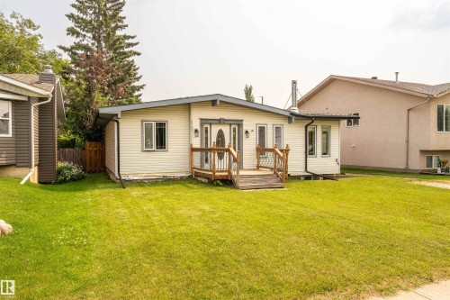 Ranch-style residence featuring light-colored siding, a front entry deck with wood railings, and a prominent front door with an oval glass insert - 5103 50 Street, Cold Lake, AB - Outdoor