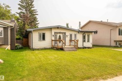 Ranch-style residence featuring light-colored siding, a front entry deck with wood railings, and a prominent front door with an oval glass insert - 