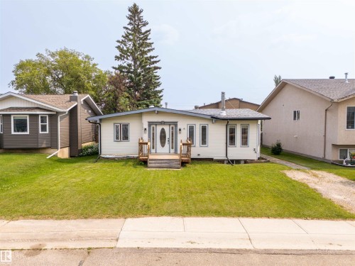 Single-story residence featuring light-colored siding, a dark roof, and a wooden front porch with railings - 5103 50 Street, Cold Lake, AB - Outdoor
