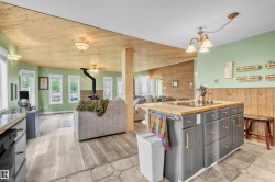 Kitchen island with integrated cooktop, light wood-finish countertop, and dark gray cabinetry featuring gold-tone hardware - 