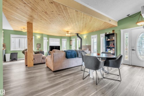 Spacious living area featuring wood-finish flooring, a wood plank ceiling, and a prominent wood-burning stove - 5103 50 Street, Cold Lake, AB - Indoor