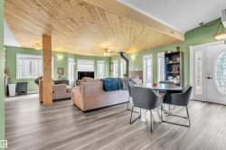 Spacious living area featuring wood-finish flooring, a wood plank ceiling, and a prominent wood-burning stove - 