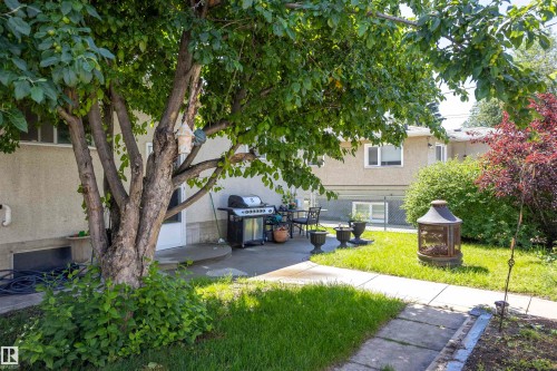 Spacious backyard featuring a concrete patio, mature trees, green lawn, and privacy fencing - 10428 68 Avenue Nw, Edmonton, AB 