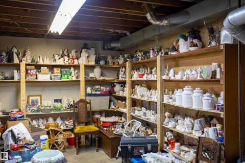 Basement area featuring exposed ceiling joists, overhead fluorescent lighting, ductwork, and extensive built-in shelving - 10428 68 Avenue Nw, Edmonton, AB 