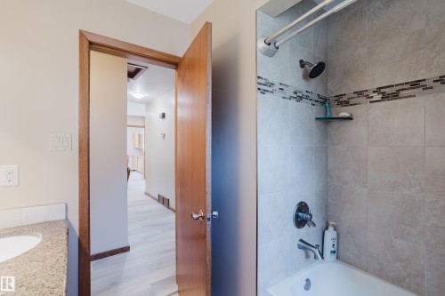 Bathtub with tiled surround featuring decorative mosaic accent band - 10924 35A Avenue Nw, Edmonton, AB 