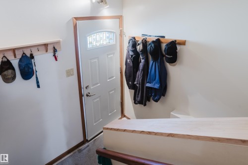 Entry door with decorative glass insert, wood trim, and a built-in wall-mounted coat rack - 10924 35A Avenue Nw, Edmonton, AB 