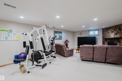 Recessed lighting, light-toned carpeting, a stone-clad fireplace, and a large television alcove - 10924 35A Avenue Nw, Edmonton, AB 