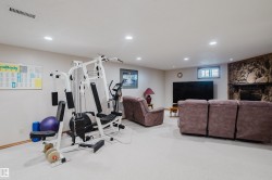 Recessed lighting, light-toned carpeting, a stone-clad fireplace, and a large television alcove - 
