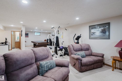 Recessed lighting illuminates a spacious room featuring a neutral color palette and carpet flooring - 10924 35A Avenue Nw, Edmonton, AB 