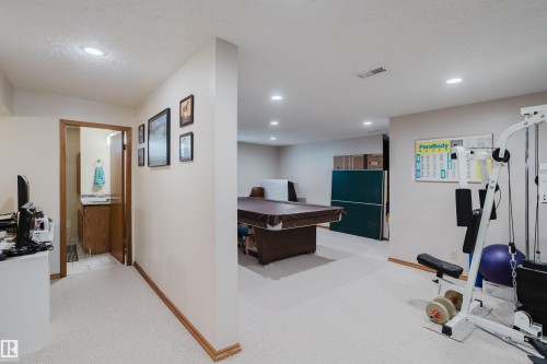 Recessed ceiling lighting, light-toned carpeting, wood trim, and an adjacent bathroom with a wood vanity - 10924 35A Avenue Nw, Edmonton, AB 