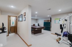 Recessed ceiling lighting, light-toned carpeting, wood trim, and an adjacent bathroom with a wood vanity - 