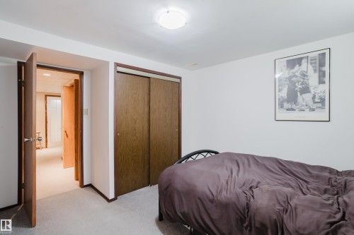 Carpeted flooring with painted walls, a flush-mount ceiling light, and a built-in closet with sliding wood-finish doors - 10924 35A Avenue Nw, Edmonton, AB 