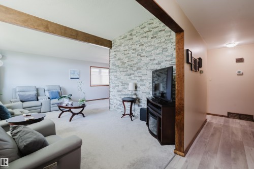 Light-toned wall-to-wall carpeting, stone-look accent wall, and wood-finish flooring - 10924 35A Avenue Nw, Edmonton, AB 