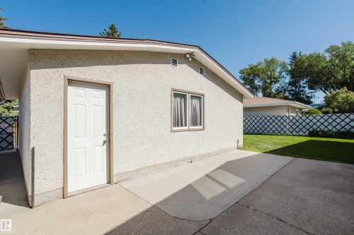 Stucco exterior with a pitched roofline, side door access, and a concrete patio - 10924 35A Avenue Nw, Edmonton, AB 