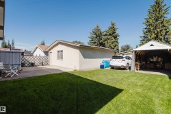 Expansive grassy yard with a concrete patio, detached garage, and a covered carport - 