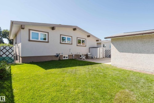 Spacious backyard with a vibrant green lawn, concrete patio, and a utility shed - 10924 35A Avenue Nw, Edmonton, AB 
