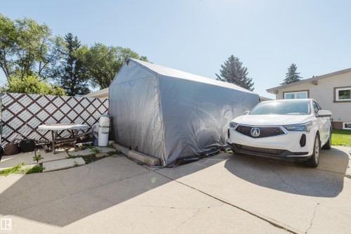 Concrete driveway and patio area, featuring a temporary storage structure and a decorative lattice fence - 10924 35A Avenue Nw, Edmonton, AB 